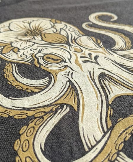 Detaillierter Siebdruck in Gold auf schwarzem T-Shirt – Octopus-Design als Beispiel für feine Linien und hohe Deckkraft.