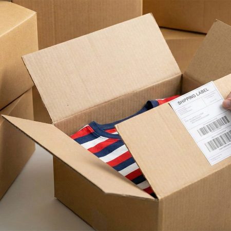Versandkarton mit T-Shirt wird für den Versand etikettiert, Print on Demand und Fulfillment Service für Onlineshops.